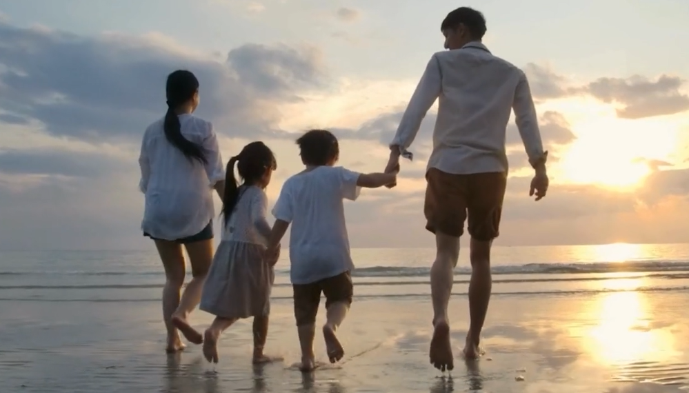 Screenshot of a family walking on the beach during a sunrise.